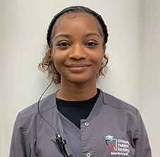 Smiling dental assistant in gray uniform at pediatric dentistry clinic