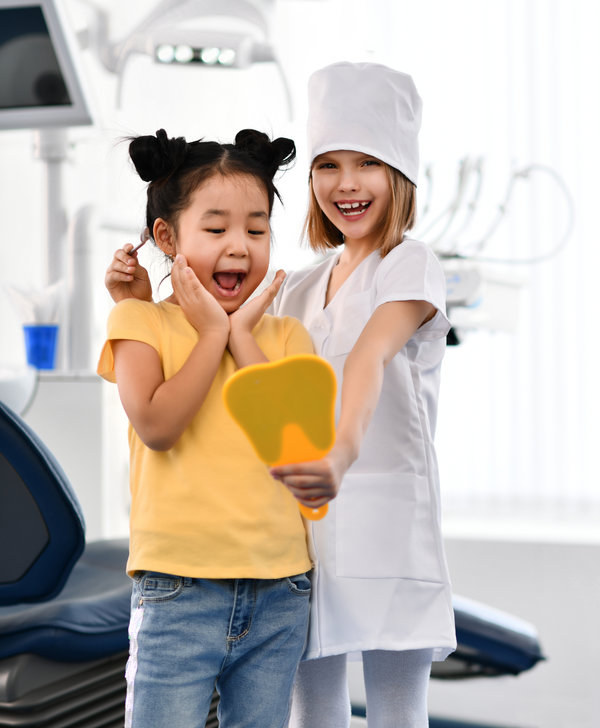 Kids girls play dentist and happy patient in dental office. Patient and stomatologist are glad to see patient healthy smile.