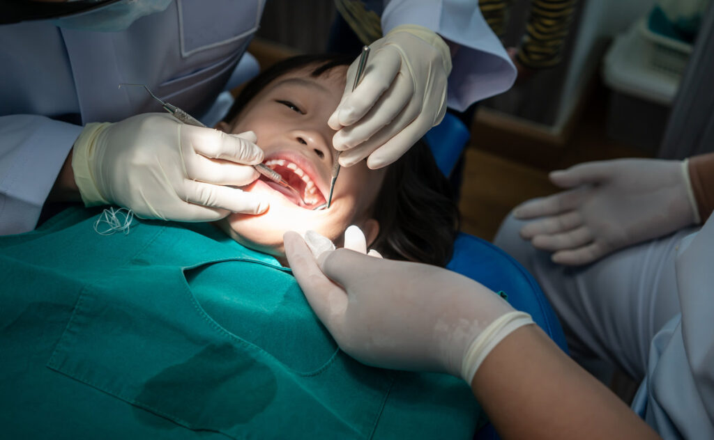 Asian girl met the dentist for routine dental checkup and consultant. Dental cleaning process.